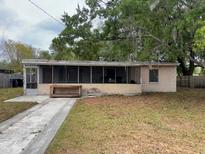 Modest single story home with screened-in porch, concrete drive and mature trees at 11625 Churchill St, Orlando, FL 32817