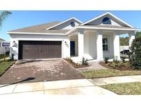 Charming single-story home with a brick driveway, two-car garage, and covered front porch with white pillars at 1374 Brentwood Dr, Kissimmee, FL 34746