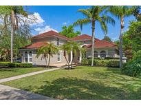 Beautiful two-story home with tile roof, well-manicured lawn, and mature palm trees at 1803 Glenbay Ct, Windermere, FL 34786