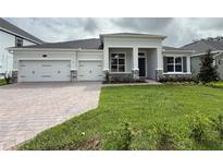 Charming single-story home boasting a manicured lawn, three-car garage, and stone accents on the facade at 2531 Blue Wave Pl, Oviedo, FL 32765