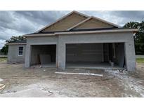 Unfinished stucco home with a three-car garage and architectural detailing under cloudy skies at 2644 Ravencliffe Ter, Oviedo, FL 32765
