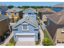 Lovely light blue home featuring a white garage door, well-manicured landscaping, and a paved driveway at 7409 Excitement Dr, Reunion, FL 34747