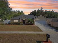 Charming single-story home with a well-manicured lawn, mature trees, and attached two car garage at 149 Southern Breeze Dr, Minneola, FL 34715