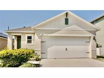A two-car garage adds curb appeal with a carriage door, manicured bushes, and a charming exterior at 156 Eagleview Loop, Davenport, FL 33837