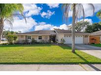 Charming single-story home with a well-manicured lawn, mature palm trees, and a two-car garage at 201 Twelve League Cir, Casselberry, FL 32707