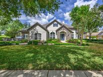 Well-maintained home with manicured lawn, beautiful stone accents, mature trees, and tile roof at 25519 Hawks Run Ln, Sorrento, FL 32776