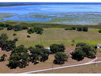 Expansive aerial view of a beautiful lakeside property with lush greenery, mature trees and a tranquil country setting at 3650 Lake Tohopekaliga Rd, St Cloud, FL 34772