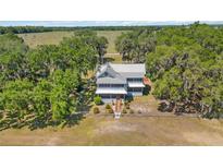 Inviting two-story home featuring a metal roof, charming front porch, and mature trees with Spanish moss at 3650 Lake Tohopekaliga Rd, St Cloud, FL 34772