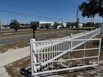 View of a fenced lot showing a white fence with gate. The area is partially paved with views of nearby buildings at 8 E Summit St, Apopka, FL 32712