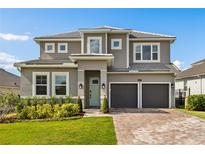 Two-story home featuring a two-car garage, brick driveway, well-manicured lawn and light-green front door at 16018 Volterra Pt, Bella Collina, FL 34756