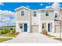 Charming townhome exterior with a blue front door, neutral paint and a one car garage with landscaping at 2413 Brook Marsh Loop, Kissimmee, FL 34747