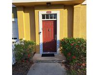 Charming townhome entrance with a red door, white trim, and vibrant red hibiscus bushes at 2618 Lodi Cir # 102, Kissimmee, FL 34746