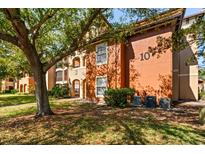 Exterior view of an apartment building with an orange facade and landscaped yard at 5524 Metrowest Blvd # 210, Orlando, FL 32811