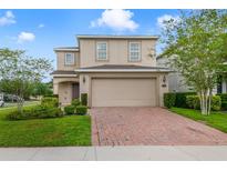 Two-story home featuring a well-maintained lawn, a brick-paved driveway, and an attached two-car garage at 1354 Riley Cir, Deland, FL 32724
