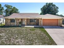 Charming single-story brick home featuring an attached garage and well-maintained front yard at 2470 Pine Tree Circle Dr, Orange City, FL 32763