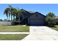 Beautiful two-story home with a well-manicured lawn and mature palm trees providing shade at 2865 Running Brook Cir, Kissimmee, FL 34744