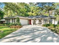 Charming home with a well-manicured lawn, a red door, and an attached two-car garage at 3517 Merivale Dr, Casselberry, FL 32707