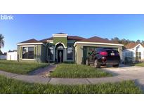 Charming single-story home featuring manicured lawn and a dark-colored SUV parked in the driveway at 8325 Sun Vista Way, Orlando, FL 32822