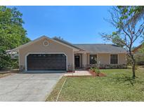 Charming single-story home with a well-manicured lawn, stone accents, and a two-car garage at 10030 Cheshunt Dr, Orlando, FL 32817