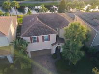 Aerial view of a two-story home with a tile roof, two-car garage, and lush landscaping in a waterfront community at 11962 Autumn Fern Ln, Orlando, FL 32827