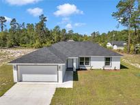 Beautiful single-story home featuring a two-car garage, well-maintained lawn, and classic white and gray color scheme at 17468 Sw 36Th Ter, Ocala, FL 34473