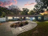 Charming single story home with an inviting circular driveway and lush landscaping at dusk at 2945 Southgate Ter, Orlando, FL 32818