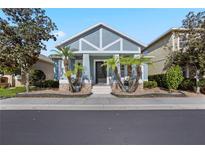 Charming blue single-Gathering home with a well-manicured front yard and inviting entryway with palm trees at 306 Balfour Dr, Winter Springs, FL 32708