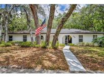 Charming white home with an American flag, trees, and lush landscaping at 1304 Deer Run Dr, Winter Springs, FL 32708