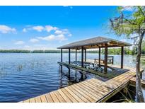 Waterfront home features a private boat dock with a boat lift on a sunny day at 16692 Lake Pickett Rd, Orlando, FL 32820