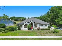 Charming single-story home with a well-manicured lawn, red door, and tasteful landscaping at 1851 Sweetwater West Cir, Apopka, FL 32712