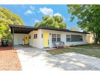 Charming single story home featuring a covered carport, manicured lawn, and bright yellow doors at 2903 E Michigan St, Orlando, FL 32806