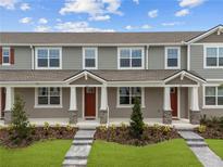 Charming townhome showcases a manicured lawn, gray siding, and inviting front porch at 3275 Gardenia Reserve St, Apopka, FL 32712