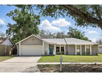 Well-kept single-story house featuring a two-car garage, blue front door, and tidy landscaping at 5163 Lighthouse Rd, Orlando, FL 32808