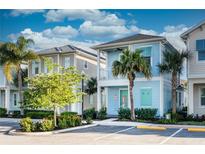 Charming light blue two-story home with a balcony and tropical landscaping under a blue sky at 8044 Dreamsicle Dr, Kissimmee, FL 34747