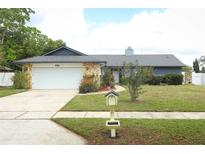 Charming single-story home featuring a two-car garage, stone accents, and a lush green lawn at 9311 Sonia St, Orlando, FL 32825