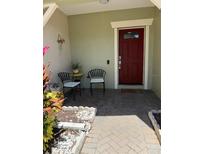 Charming front porch with a welcoming red door, seating and beautiful plants at 9978 Tivoli Villa Dr, Orlando, FL 32829