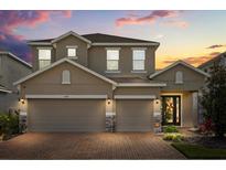 Charming two-story home with a brick driveway and a well-manicured lawn at sunset at 1109 Castlevecchio Loop, Orlando, FL 32825