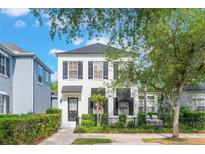 Charming two-story home with black shutters, a landscaped yard, and shade trees at 1117 Damask St, Celebration, FL 34747