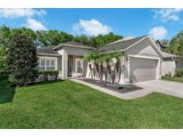 Inviting single-story home with a well-manicured lawn, lush landscaping, and a two-car garage at 145 Circle Hill Rd, Sanford, FL 32773
