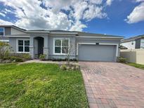 Charming single Gathering home with a brick driveway, two-car garage, and manicured lawn under a cloudy blue sky at 2741 Nottel Dr, St Cloud, FL 34772