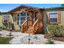 Charming home featuring a custom-built porch with wooden stairs and stone landscaping at 400 N Main Ave, Minneola, FL 34715