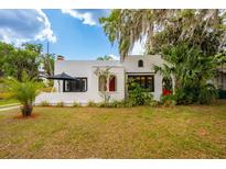 Charming stucco home featuring a red front door, well-manicured lawn, and lush landscaping at 420 N Center St, Eustis, FL 32726