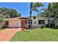 Charming single-story home featuring a well-manicured lawn, palm trees, and a cozy seating area on the front porch at 505 S Cooper St, New Smyrna Beach, FL 32169