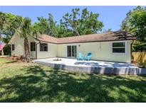 Charming home featuring a patio with chairs and a well-manicured lawn surrounded by lush trees at 1635 Magnolia Ave, South Daytona, FL 32119