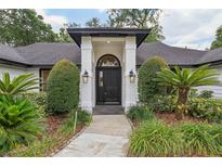 Inviting front entrance featuring a black door, white brick pillars, and professionally landscaped yard at 216 Shady Oaks Cir, Lake Mary, FL 32746
