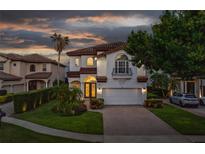 Stunning two-story home with well-manicured landscaping and a paver driveway at dusk at 8125 Via Rosa, Orlando, FL 32836