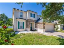 Charming two-story home features green shutters, a stone accent wall, and well-maintained landscaping at 13247 Hatherton Cir, Orlando, FL 32832