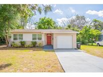 Charming single-story home featuring a red door, front yard, and attached one car garage at 1411 N Powers Dr, Orlando, FL 32818