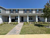 Charming two-story townhome features a landscaped yard, covered porch with columns and brick walkway at 15098 Windflower Aly, Winter Garden, FL 34787