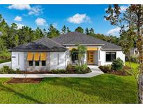Inviting single-story home featuring white exterior, yellow front door, well-manicured lawn, and lush landscaping at 18026 Reynolds Pkwy, Orlando, FL 32833